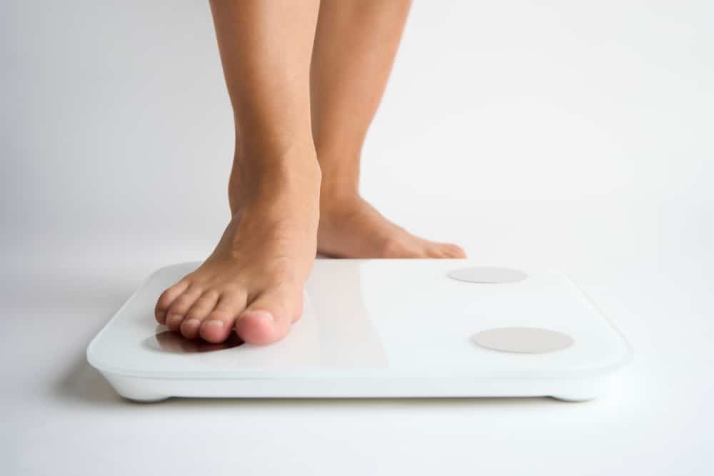 Woman steps onto a bathroom scale to confirm that her weight has been stable lately