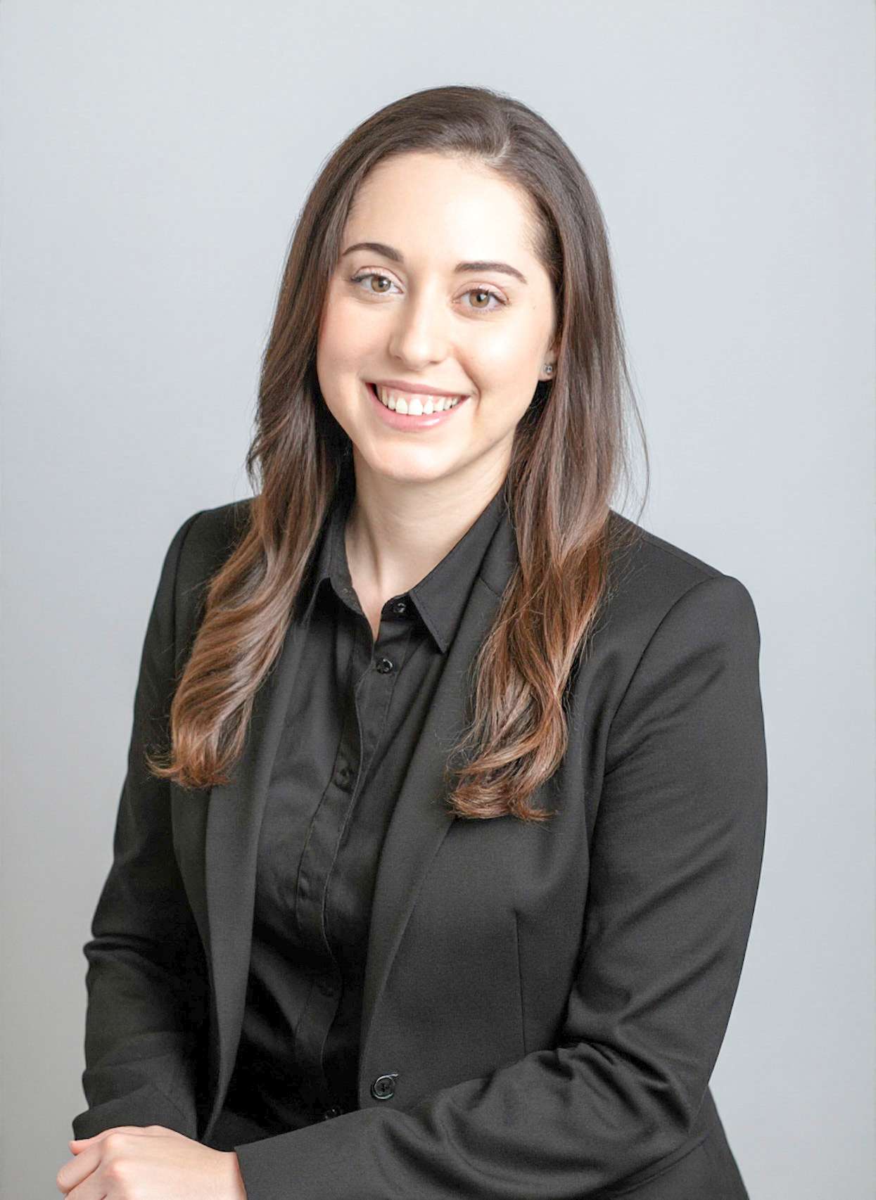 Woman in black blazer against gray backdrop